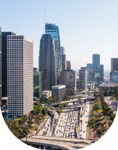 Vista aérea de una transitada autopista rodeada de modernos edificios de gran altura en un bullicioso paisaje urbano en un día claro.