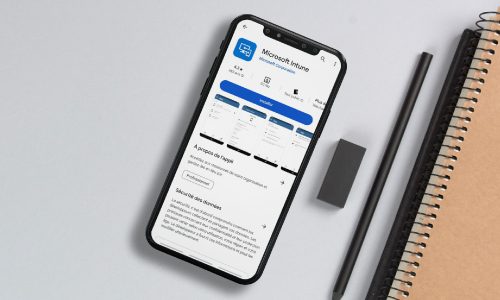 Teléfono inteligente sobre un escritorio que muestra la aplicación Microsoft Intune en Google Play Store, junto a un cuaderno, un lápiz y un borrador.