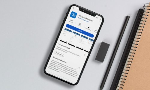 img-intune Teléfono inteligente sobre un escritorio que muestra la aplicación Microsoft Intune en Google Play Store, junto a un cuaderno, un lápiz y un borrador.